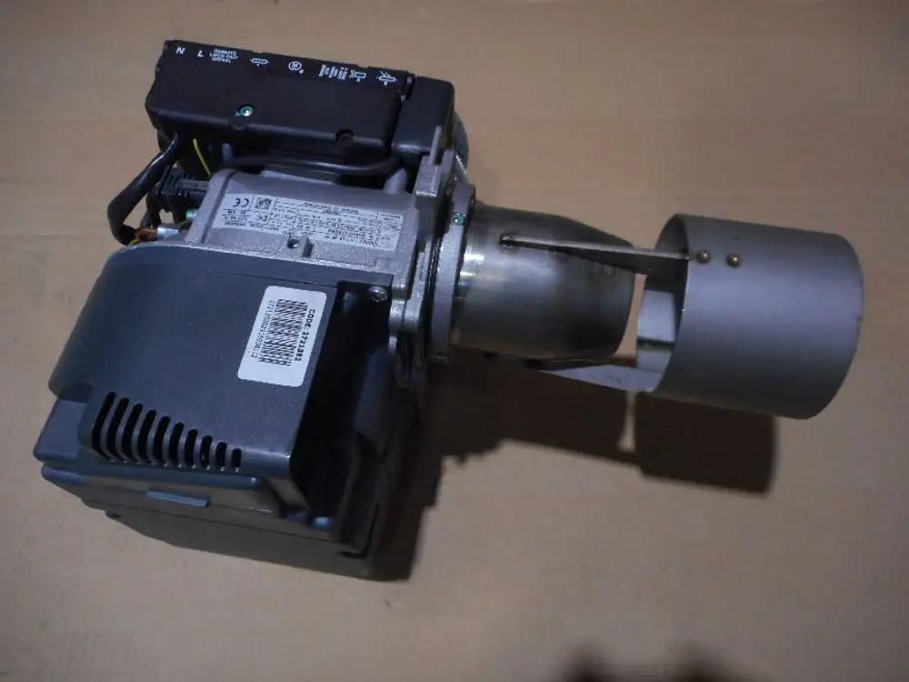 Brenner von Remeha, mit einem kompakten Design, Metallgehäuse und Auslassrohr. Sichtbare Anschlussklemmen und mögliche Hinweise auf elektrische Spezifikationen.